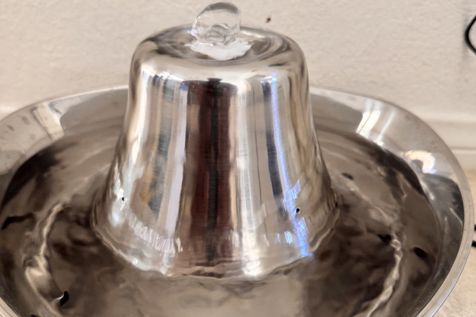 A stainless steel cat water fountain running on a tile floor
